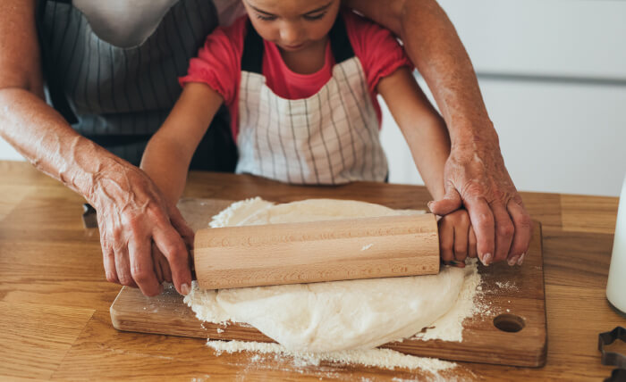 Child and Adult Using Rolling Pin Together